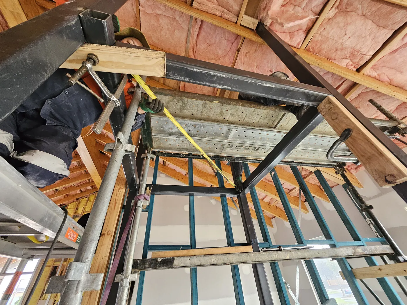 Spirit level, timber packers and clamps holding lift shaft steel in position at the head of the shaft